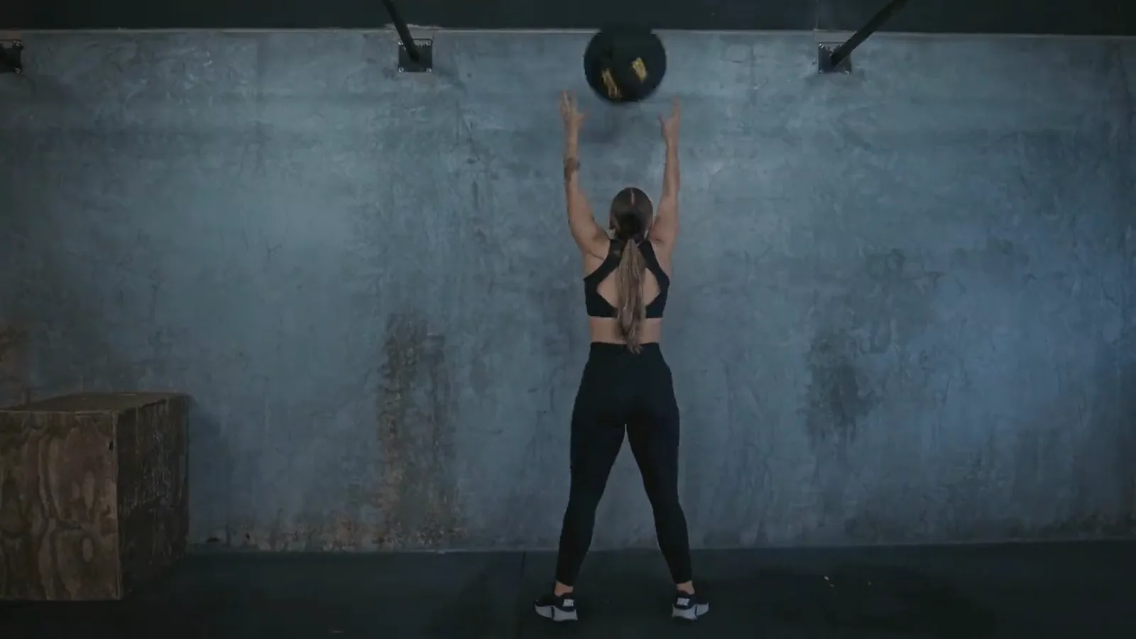 A woman performing a wall-ball throw during a strength training session
